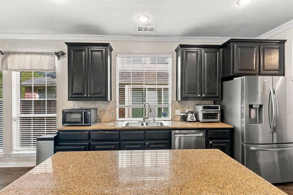 1905 Canyon Wren Drive, McKinney, TX 75071 Modern kitchen featuring dark cabinetry with raised-panel doors, stainless steel French-door refrigerator, and a large island