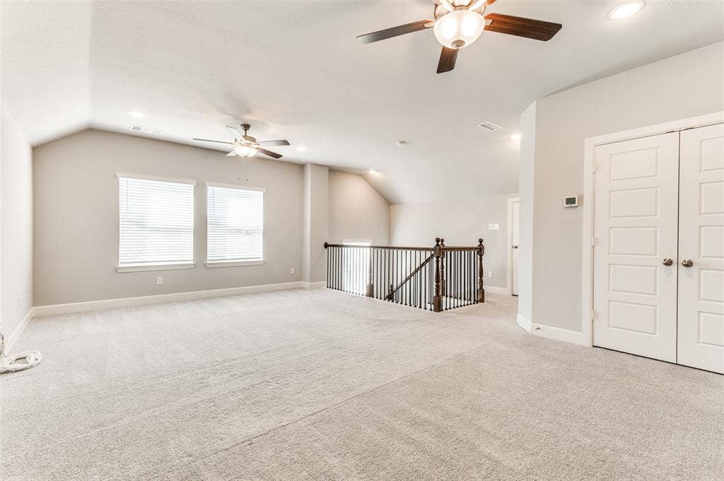 636 Courtyard Lane, Irving, TX 75039 Spacious carpeted area with vaulted ceilings, multiple windows with blinds, and recessed lighting