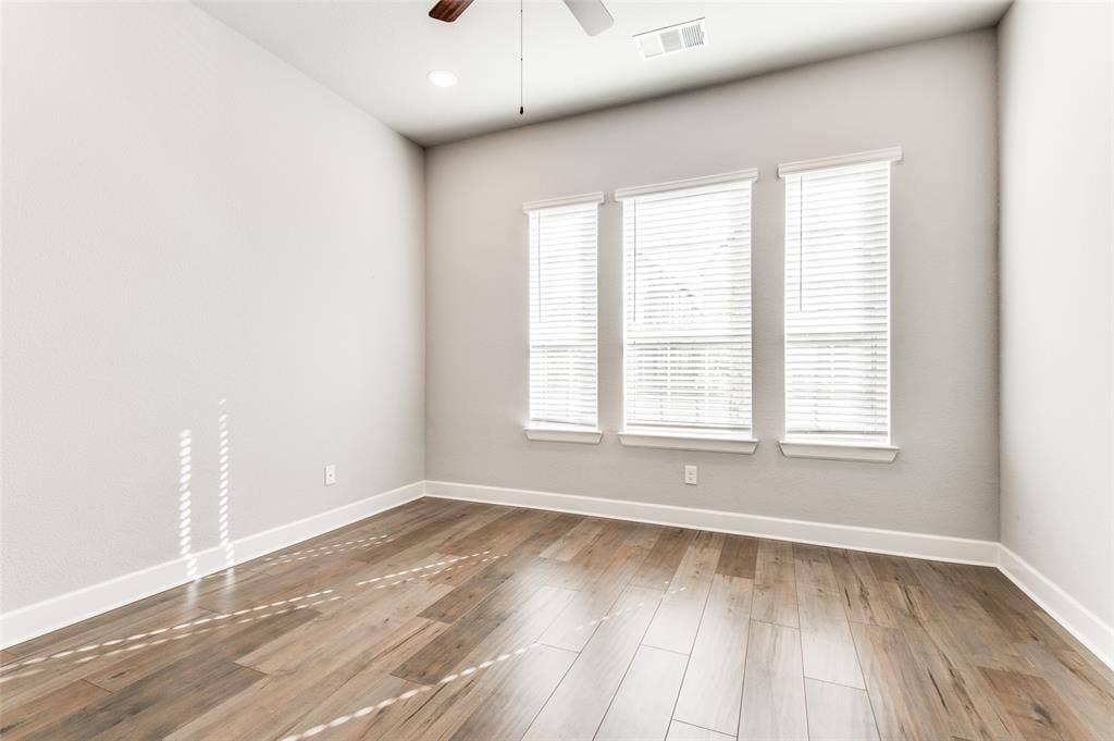 636 Courtyard Lane, Irving, TX 75039 Wood-finish flooring, three windows with blinds, recessed ceiling light, ceiling fan, and white trim