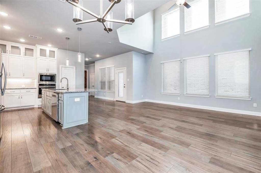 636 Courtyard Lane, Irving, TX 75039 Open-concept living area with high ceilings, wood-finish flooring, a contemporary chandelier, and a kitchen island with pendant lighting
