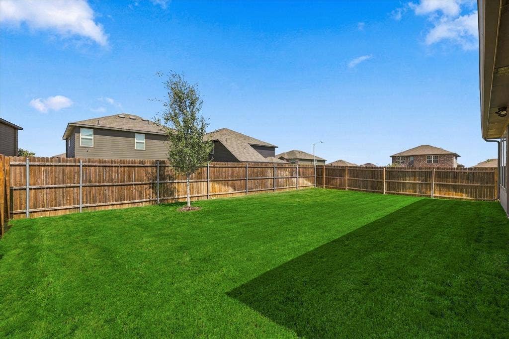 6304 Jib Court, Fort Worth, TX 76179 Expansive backyard featuring a manicured lawn, full privacy fencing, and a young tree