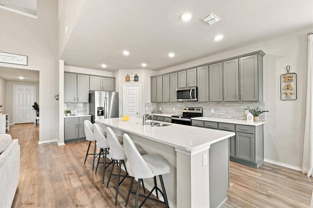 6304 Jib Court, Fort Worth, TX 76179 Kitchen featuring a large island with white countertop, recessed lighting, wood-finish flooring, and gray cabinetry with stainless steel appliances