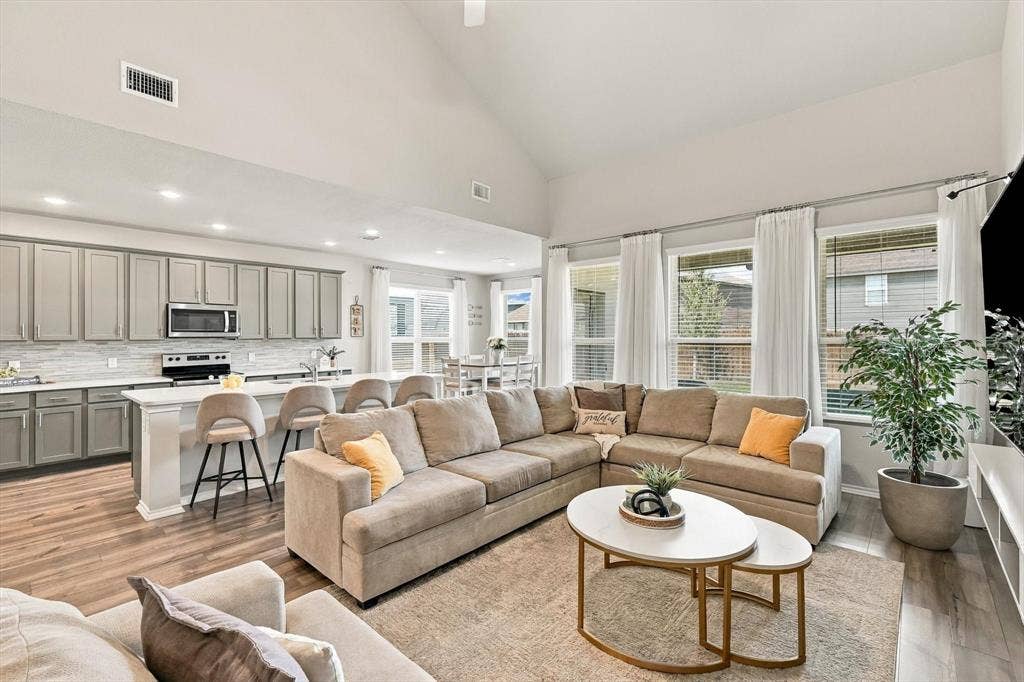 6304 Jib Court, Fort Worth, TX 76179 Vaulted ceiling, open-concept living space, wood-finish flooring, island with breakfast bar seating, and stainless steel appliances