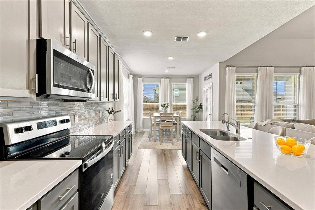 6304 Jib Court, Fort Worth, TX 76179 Gourmet kitchen featuring a large island, stainless steel appliances, crisp white countertops, and wood-finish flooring
