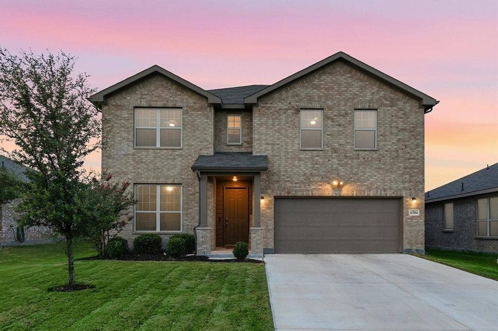 6304 Jib Court, Fort Worth, TX 76179 Two-story brick exterior with a gabled roofline, attached two-car garage, concrete driveway, and a covered entry with stone columns