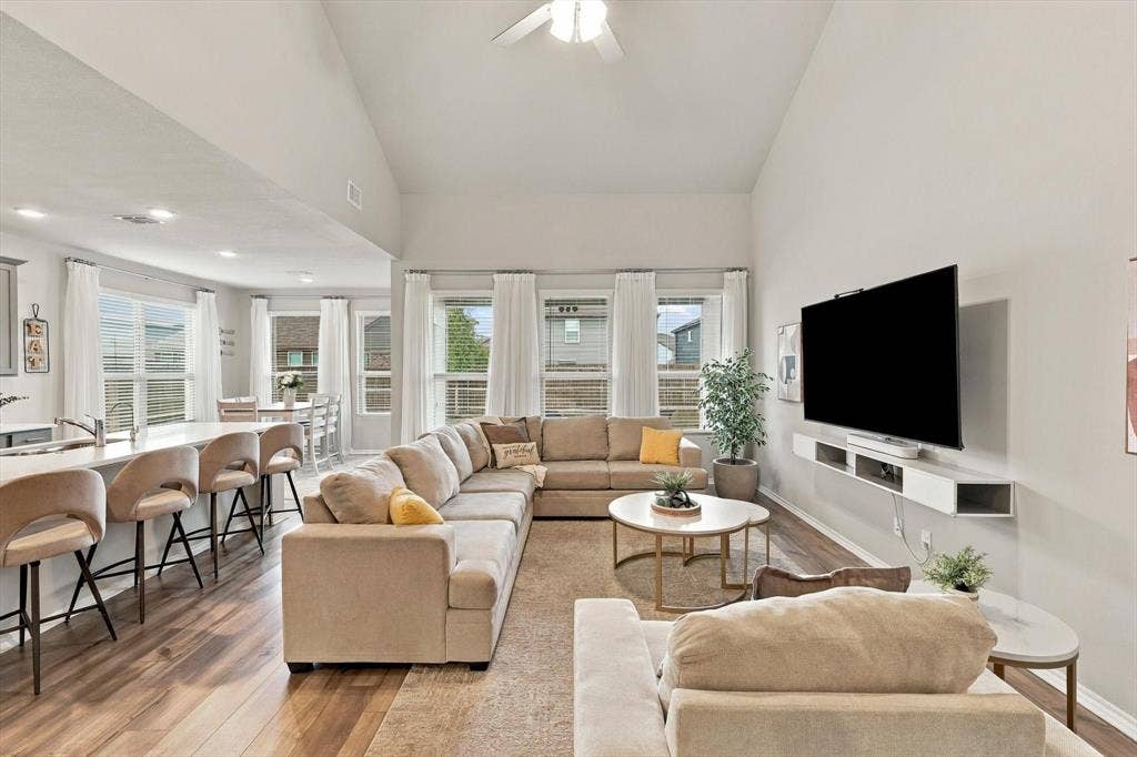 6304 Jib Court, Fort Worth, TX 76179 Open-concept living area featuring vaulted ceilings, wood-finish flooring, a kitchen island with seating, and multiple large windows