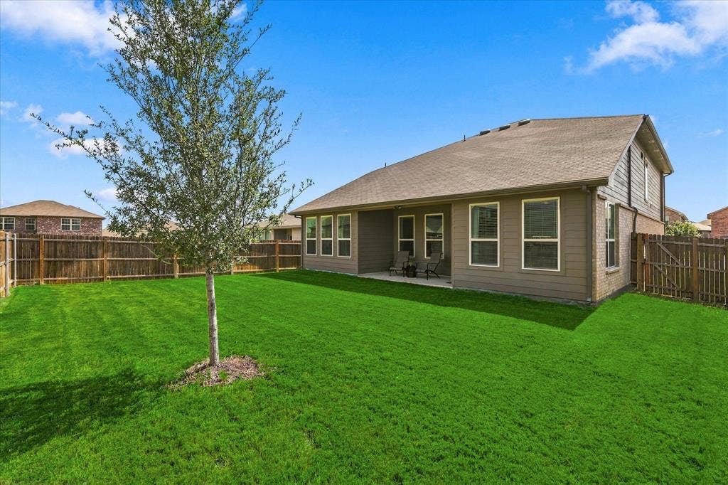 6304 Jib Court, Fort Worth, TX 76179 Expansive grass lawn with a young tree, leading to a covered patio