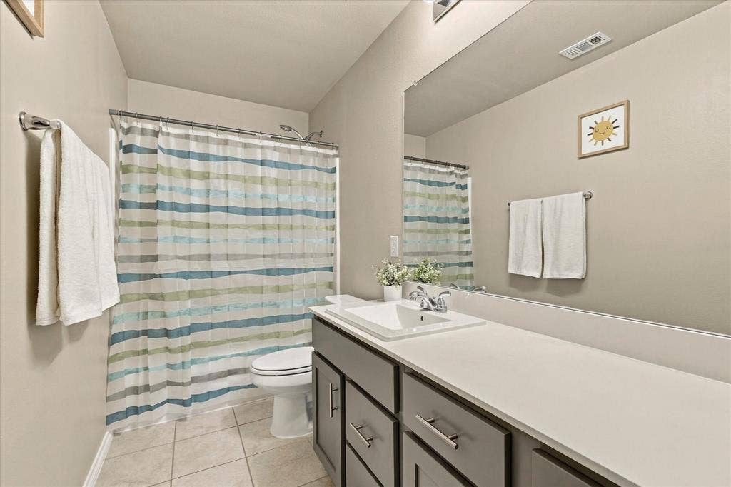 6304 Jib Court, Fort Worth, TX 76179 Bathroom featuring a single vanity with a white countertop, chrome fixtures, built-in cabinetry with brushed nickel pulls, a shower-tub combination, and tiled flooring