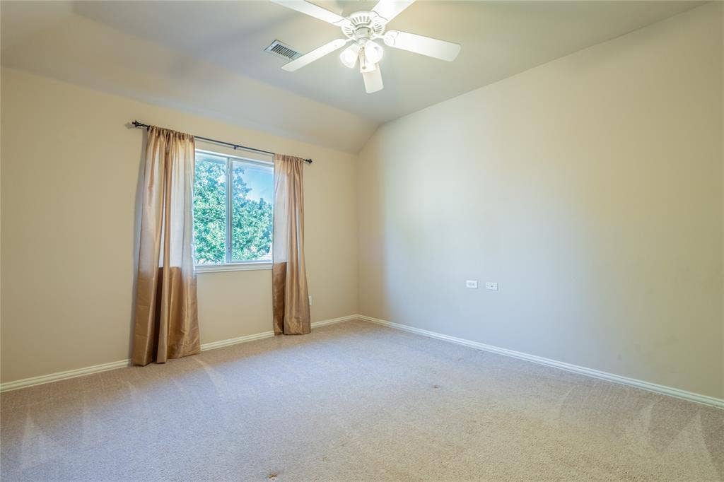 Another view of the bedroom with a recessed window with white trim, beige wall finishes, and a ceiling fan with integrated lighting