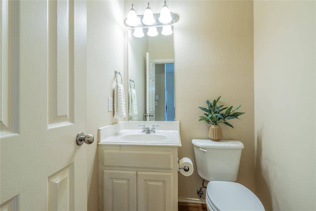 Half bath downstairs with white vanity with an integrated sink and chrome faucet