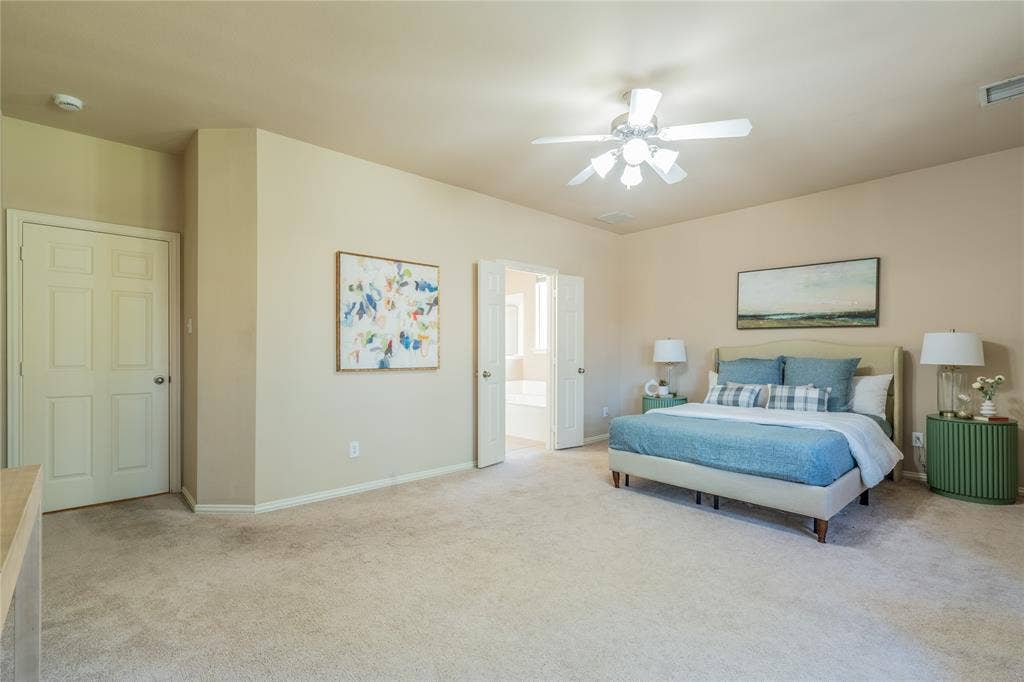 Another view of the primary bedroom with  neutral tone walls, ceiling fan with integrated lighting, door with six-panel design, and carpeted flooring