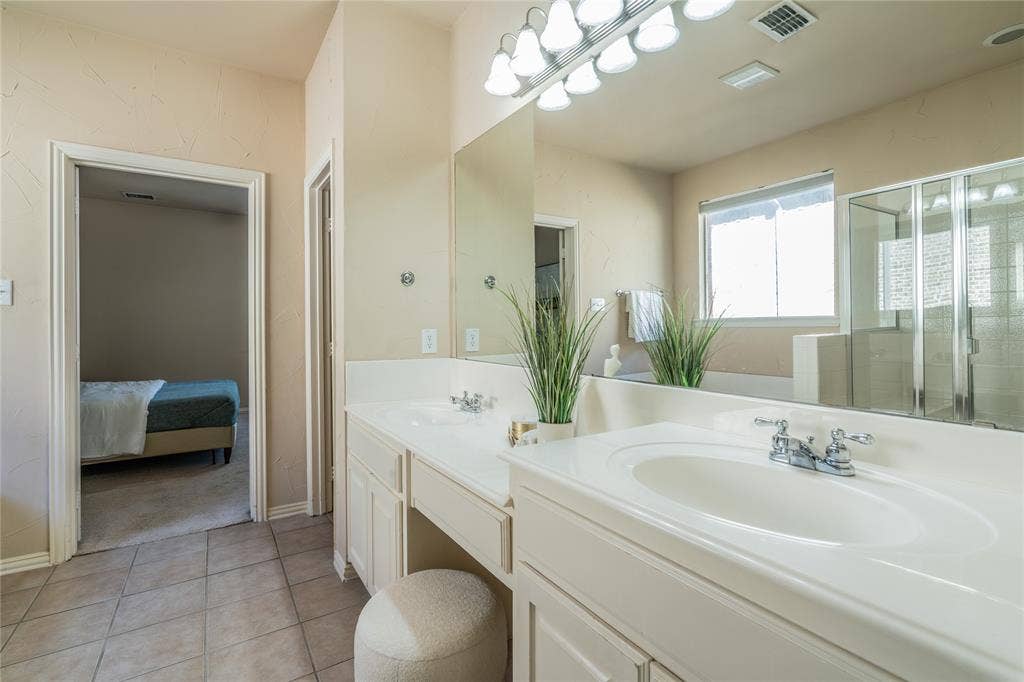 Primary bathroom with dual vanity with integrated sinks, chrome fixtures, and built-in cabinetry