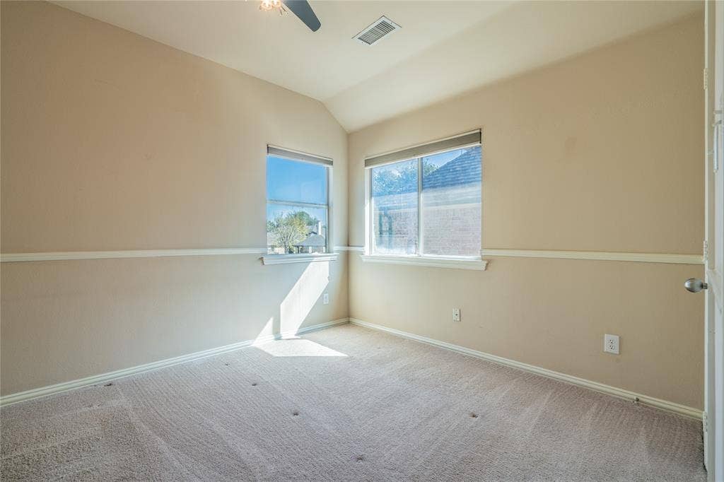 Bedroom with vaulted ceiling with a ceiling fan, carpeted flooring, and multiple windows