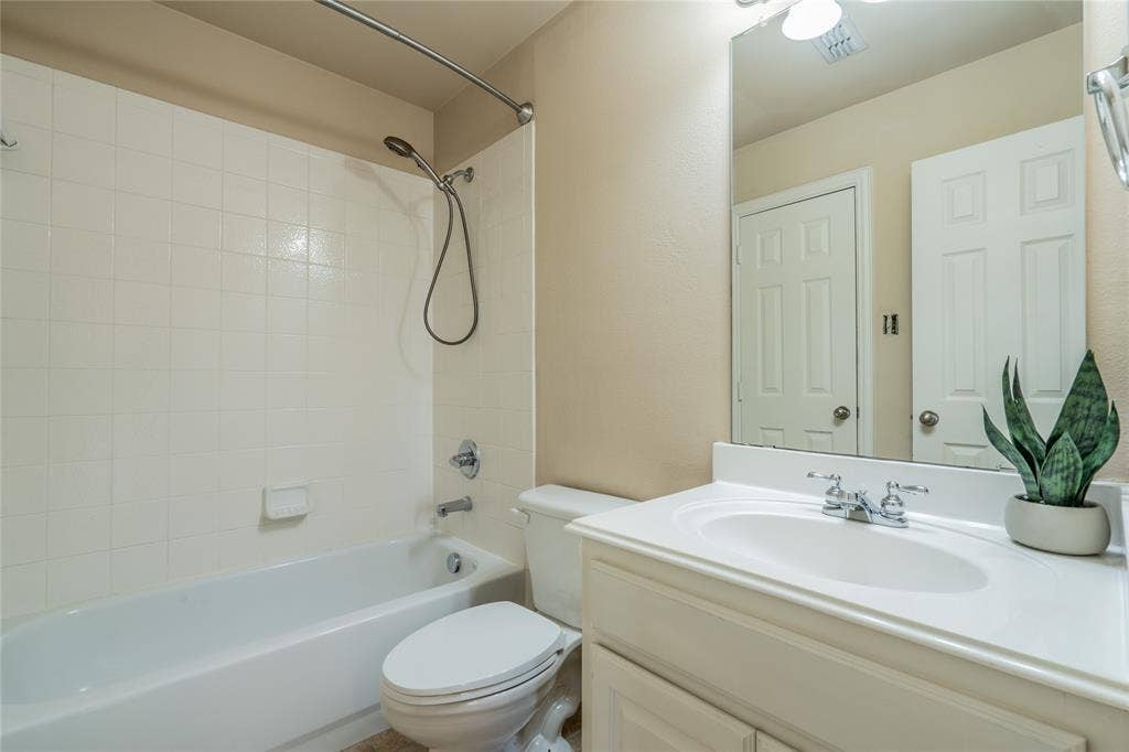 Second upstairs bathroom with white tile shower surround, chrome shower fixtures, white bathtub, white vanity with integrated sink, chrome vanity faucet