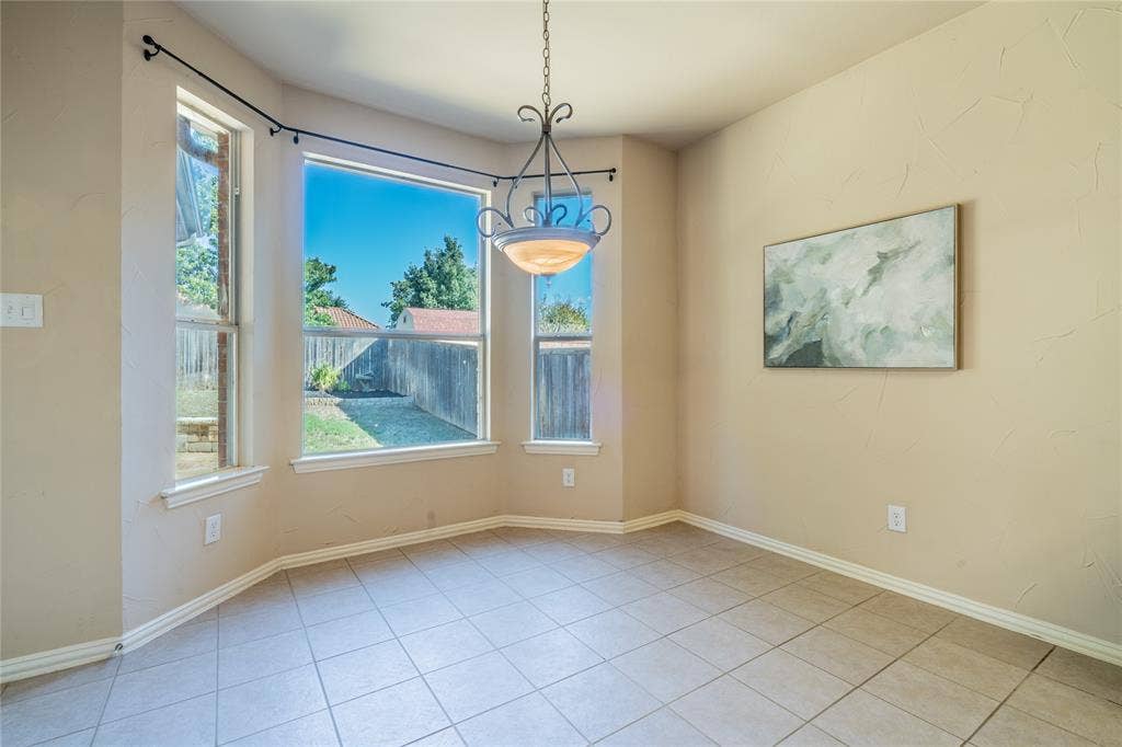 Breakfast area with bay windows, neutral wall color, tile flooring, white trim, and a decorative ceiling light fixture
