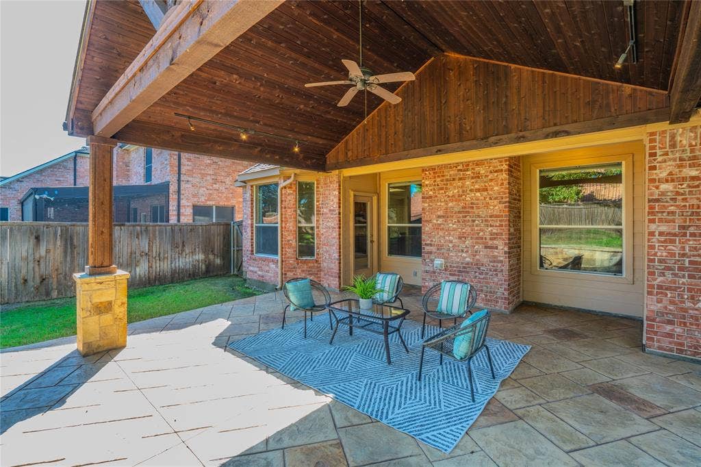 Covered patio with a wood-plank ceiling, exposed wood beams, and a ceiling fan