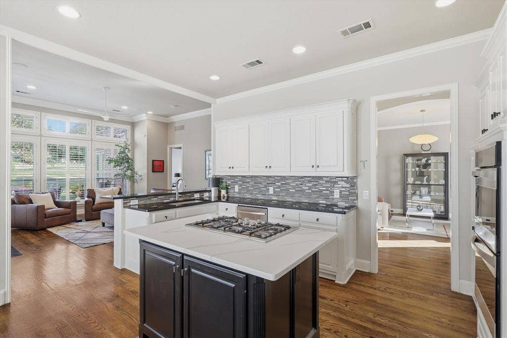 5600 Southern Hills Drive, Frisco, TX 75034 Opening to the family room, the kitchen balances classic white cabinets with a contrasting island and stainless-steel appliances.