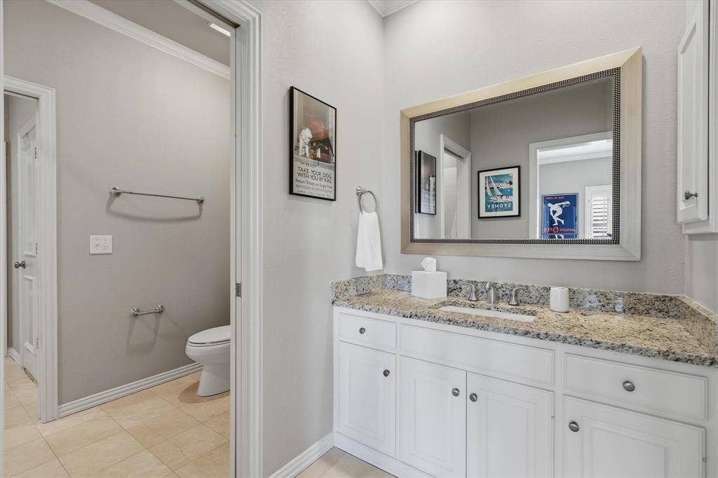 5600 Southern Hills Drive, Frisco, TX 75034 The updated Jack-and-Jill bath features white cabinetry, a stone-topped vanity and a separate water closet and bath/shower area.
