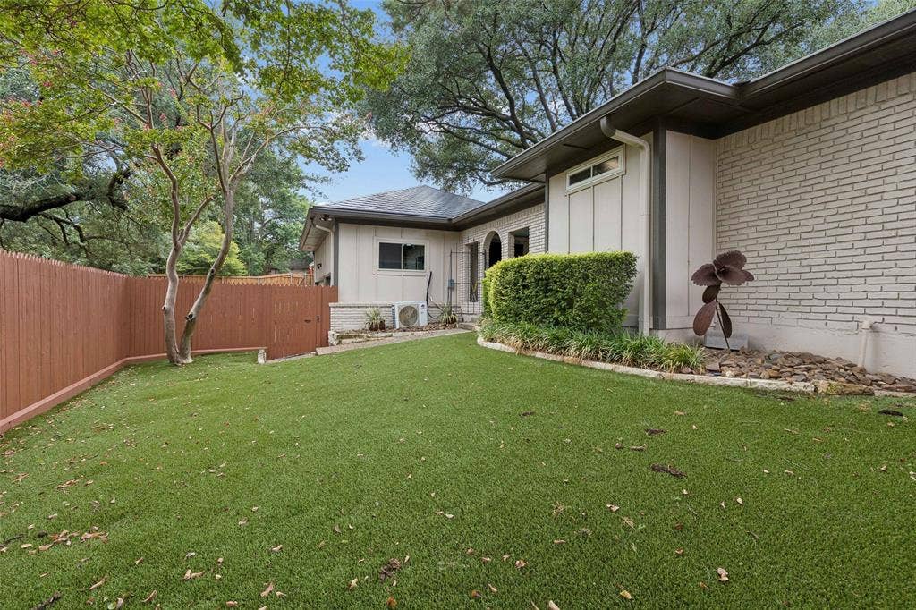 Low-Maintenance Turf Backyard — The expansive turf lawn provides a clean, green outdoor area with less upkeep, framed by mature trees and privacy fencing.