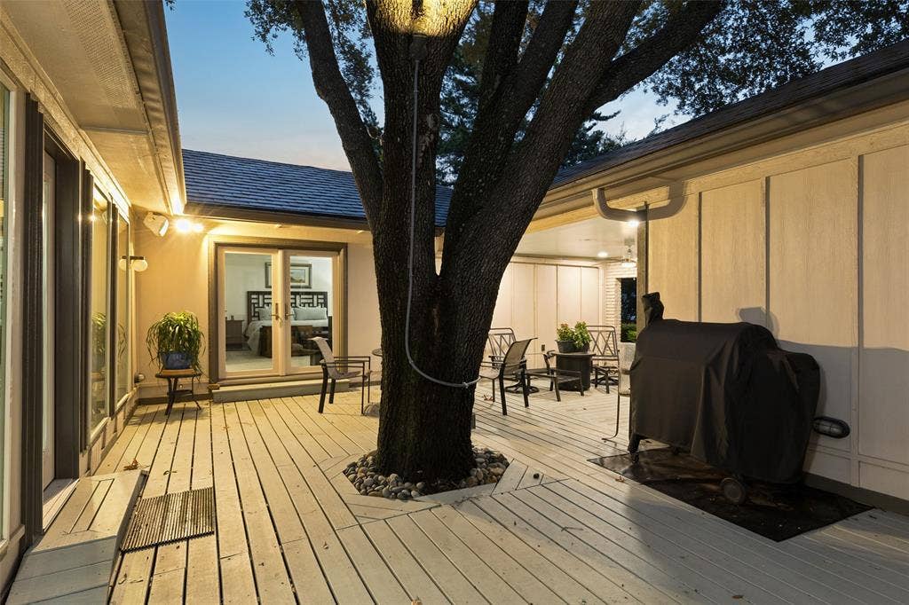 Courtyard Ambiance After Dark — Evening lighting highlights the courtyard’s mature trees and multiple access points, creating a warm setting for unwinding outdoors after sunset.