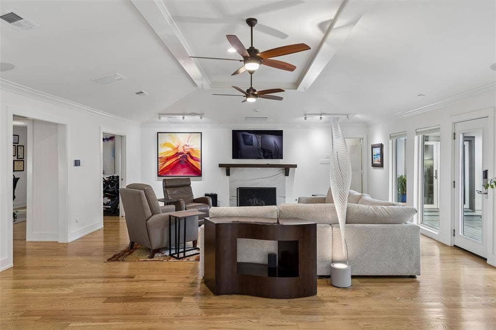 Spacious Living at the Heart of the Home — This generously sized living area offers expansive hardwood flooring, a raised ceiling treatment, multiple seating zones, and direct access to the outdoor living spaces.
