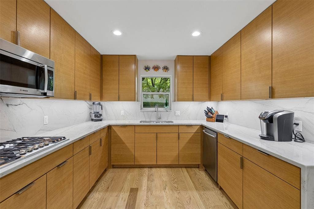 Cook-Friendly Layout with Gas Cooking — The gas cooktop sits within a broad stretch of counter space, surrounded by abundant cabinetry that keeps prep tools, cookware, and everyday essentials close at hand.