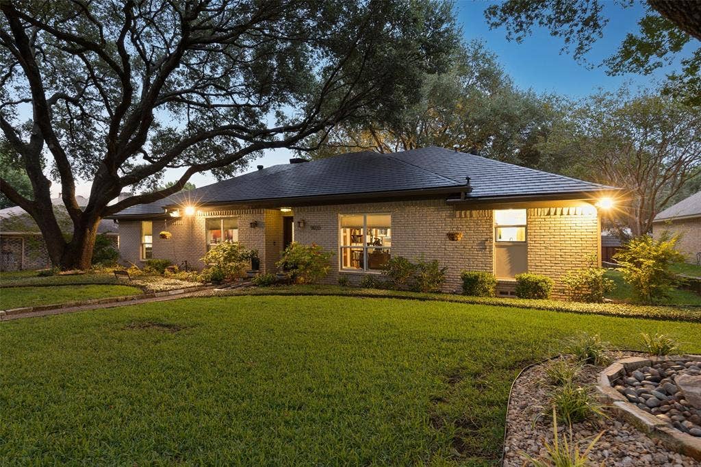 Timeless Curb Appeal — Mature trees frame the single-story brick exterior, while established landscaping and a broad front lawn give the home a welcoming, well-established presence.