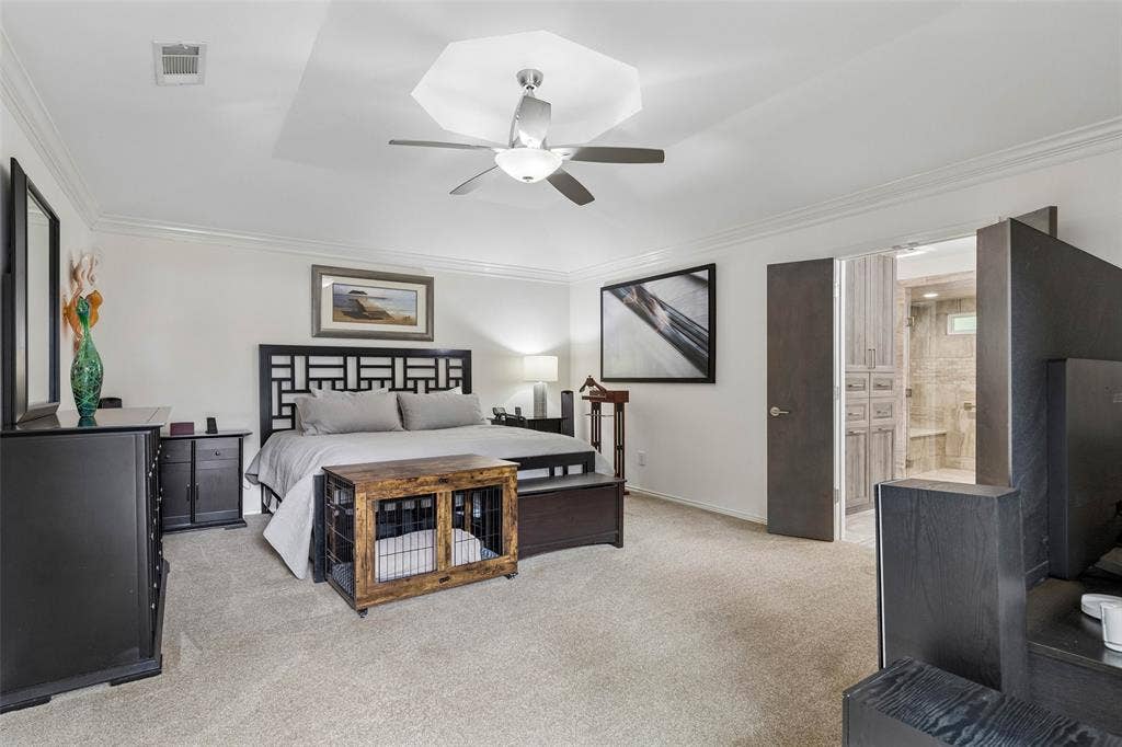Spacious Primary Retreat — The primary bedroom offers a generous footprint, soft carpeting, crown molding, and direct access to the remodeled bath for a comfortable private retreat.