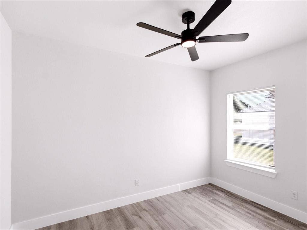 105 Oak Ridge Road, Mabank, TX 75156 Bright room featuring a window with horizontal blinds, wood-finish flooring, a ceiling-mounted fan with integrated lighting, and neutral wall finishes
