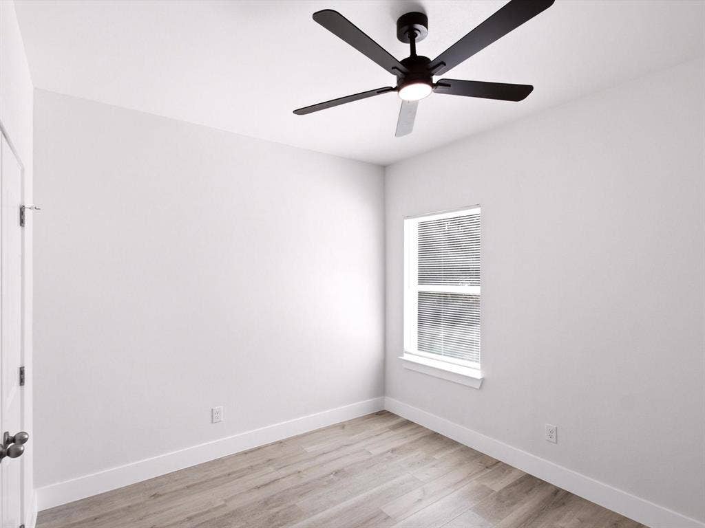 105 Oak Ridge Road, Mabank, TX 75156 Neutral paint palette with wood-finish flooring, a window with blinds, a white door, and a ceiling fan with integrated lighting