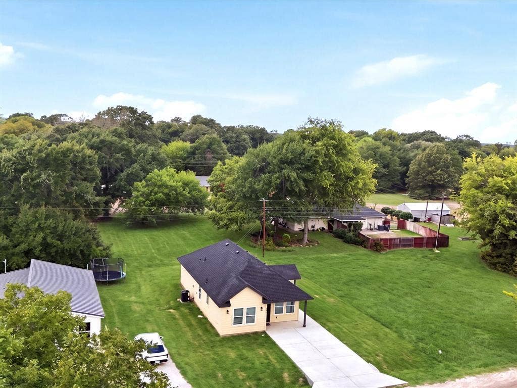 105 Oak Ridge Road, Mabank, TX 75156 Light-colored exterior with a dark shingle roof, expansive green lawn, and mature trees