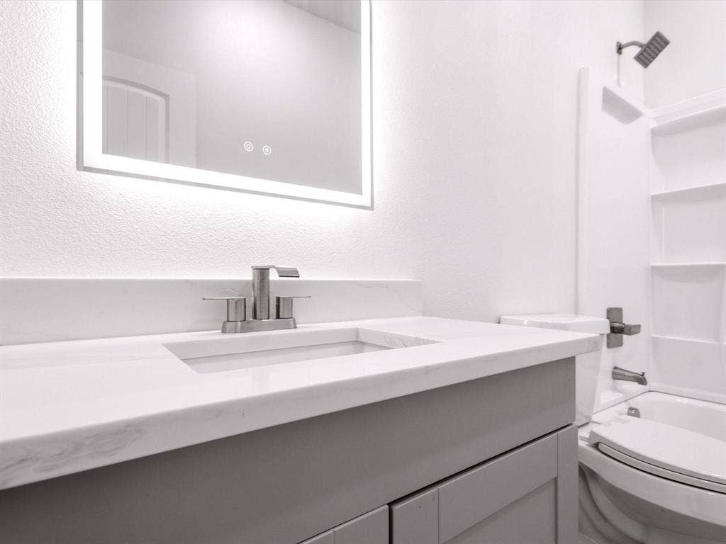 105 Oak Ridge Road, Mabank, TX 75156 Vanity with a light gray finish, solid surface countertop, integrated sink, and an illuminated mirror