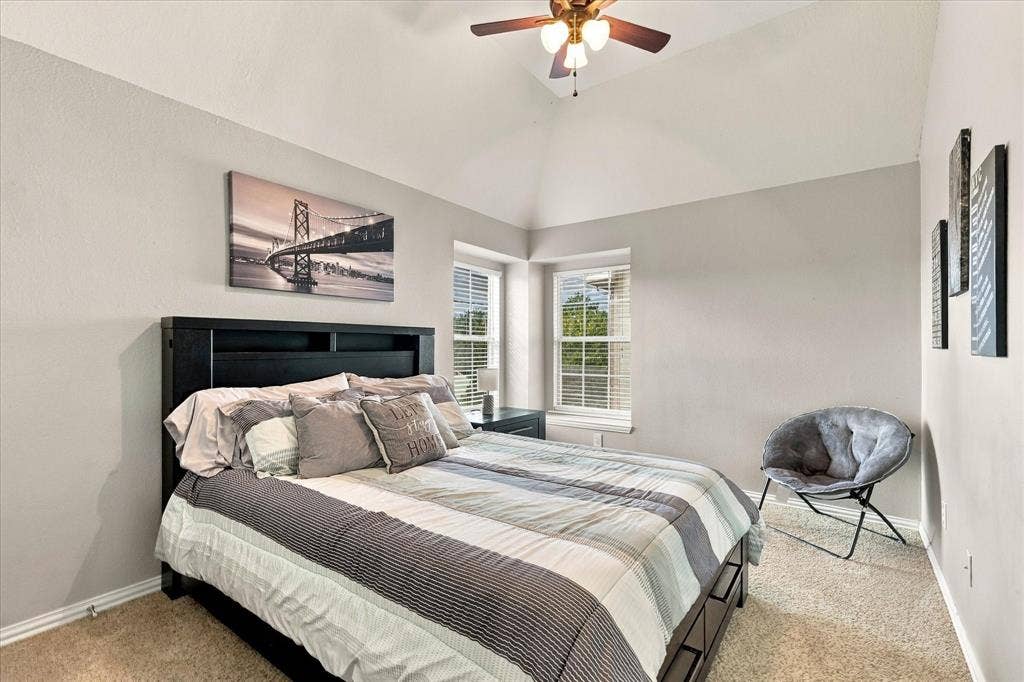 Vaulted ceilings featuring a central ceiling fan with integrated lighting and two windows with horizontal blinds