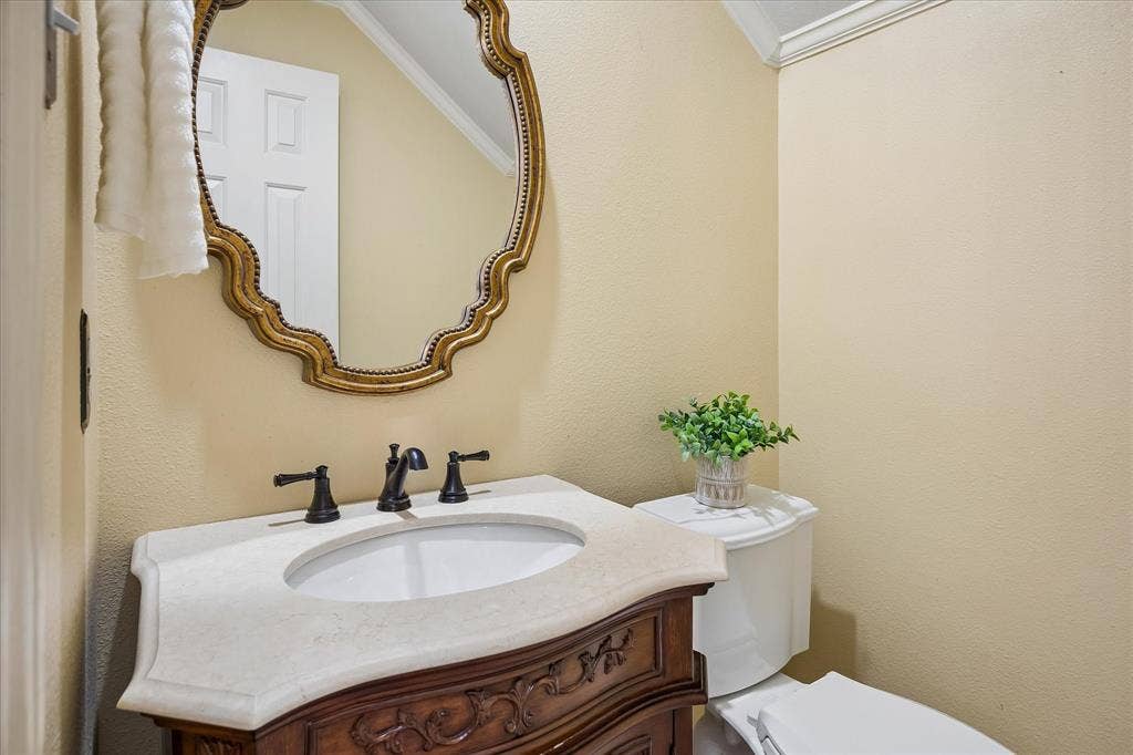 2204 Creekside Circle S, Irving, TX 75063 Ornate framed mirror over a custom cut marble vanity with an integrated sink and bronze fixtures