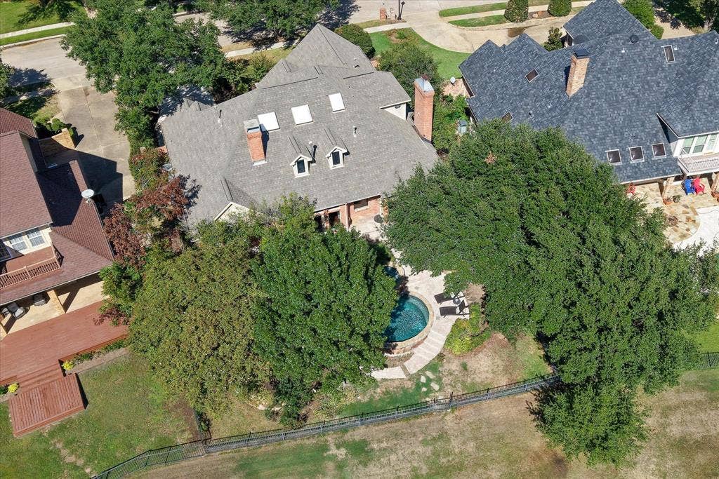 2204 Creekside Circle S, Irving, TX 75063 Exterior with a multi-gabled roofline, multiple dormer windows, and skylights amongst mature trees for plenty of shade from the Texas sun!
