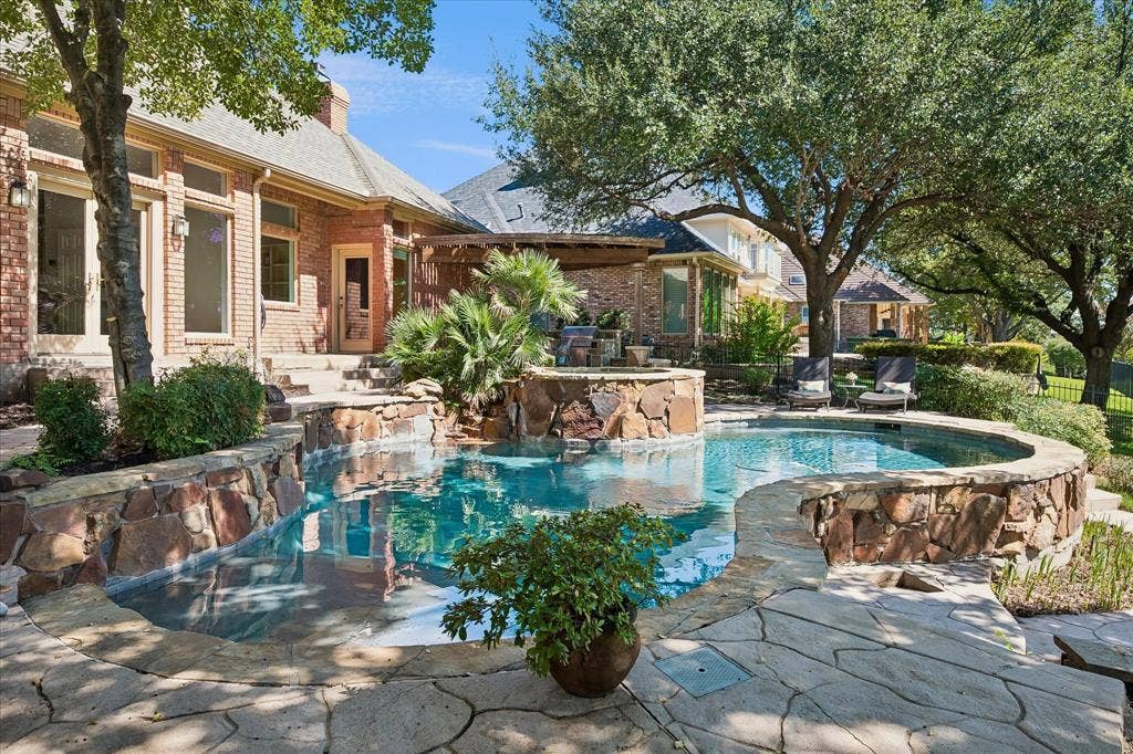 2204 Creekside Circle S, Irving, TX 75063 Curved swimming pool with a natural stone surround, flagstone patio, and mature trees