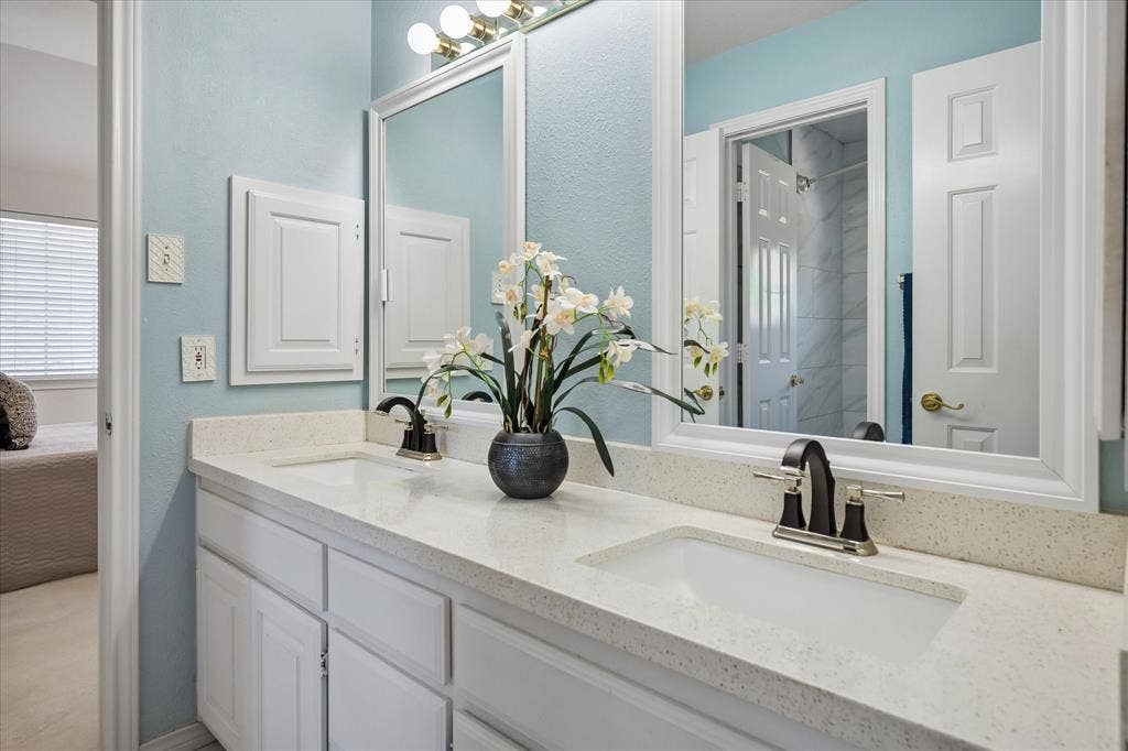 2204 Creekside Circle S, Irving, TX 75063 Dual vanity with undermount sinks, quartz countertops, and white cabinetry with dual medicine cabinets for additional storage