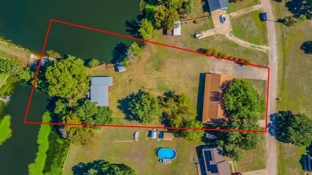118 Spring Lake Drive, Lacy Lakeview, TX 76705 Waterfront property featuring direct water access on both sides, a main residence with a brown shingle roof, and a 2 level workshop/RV storage area with a metal roof