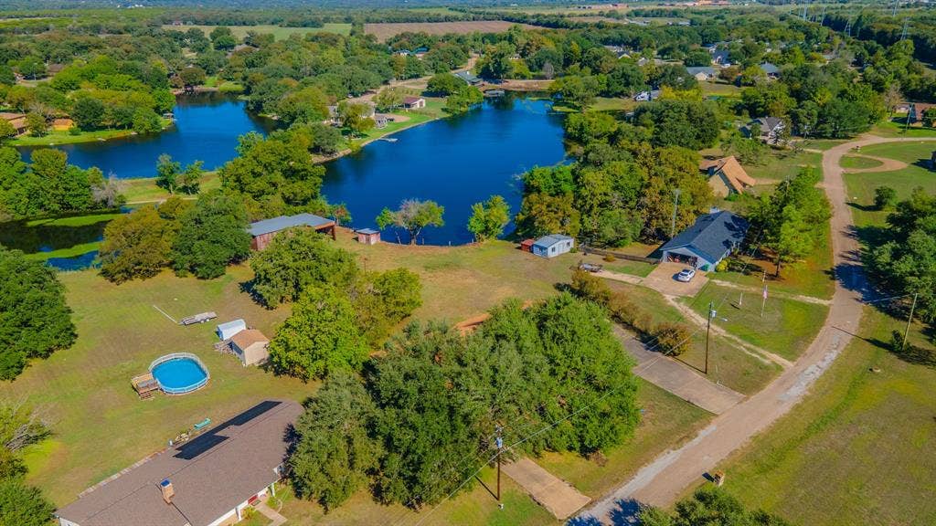 118 Spring Lake Drive, Lacy Lakeview, TX 76705 Expansive property featuring multiple structures, mature trees, a residence with an attached garage, and bordered by 2 bodies of water.