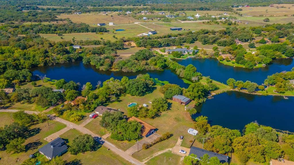 118 Spring Lake Drive, Lacy Lakeview, TX 76705 Expansive aerial landscape featuring multiple bodies of water, abundant mature trees, and surrounding residential properties