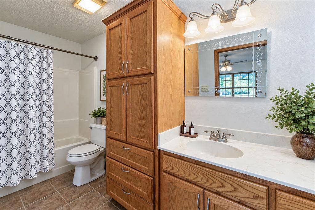 118 Spring Lake Drive, Lacy Lakeview, TX 76705 Bathroom featuring a single vanity with an integrated sink, a built-in wood-finish storage cabinet, a tub with a shower, and tiled flooring