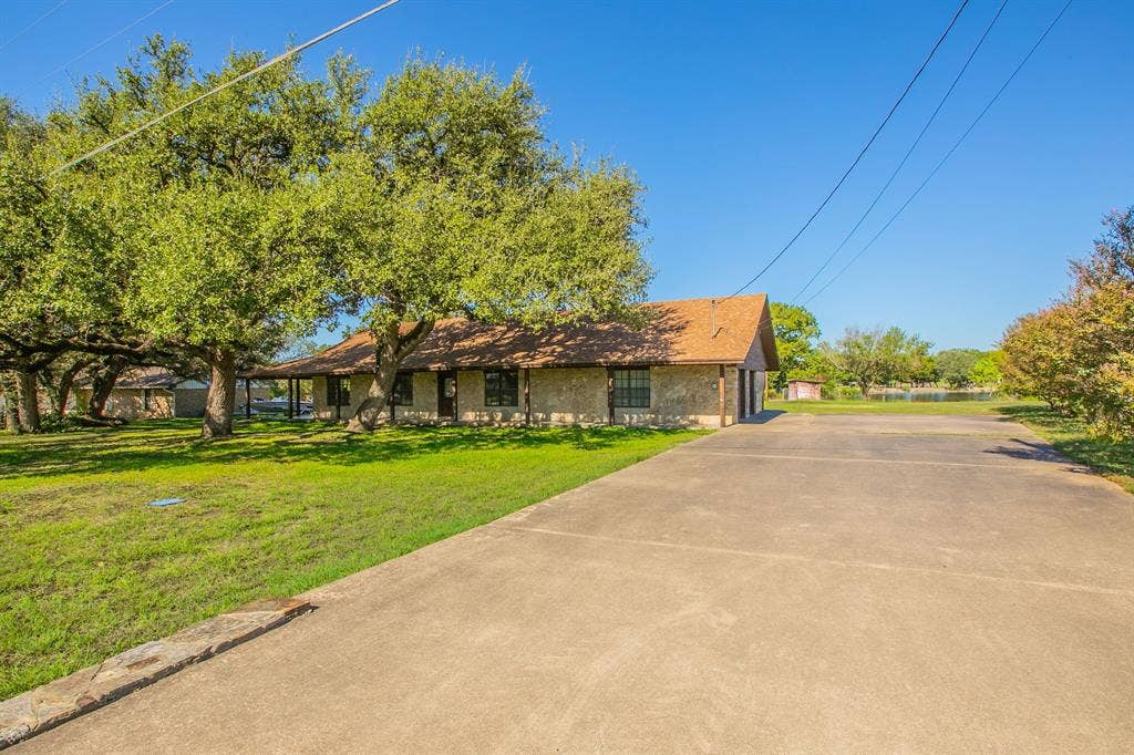 118 Spring Lake Drive, Lacy Lakeview, TX 76705 Stone exterior residence with a covered front porch, concrete driveway leading to a 2 car side garage and mature trees