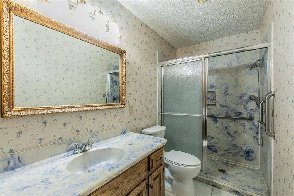 118 Spring Lake Drive, Lacy Lakeview, TX 76705 Vanity with an integrated sink and blue-swirl countertop, wood-finish cabinetry, and an ornate framed mirror