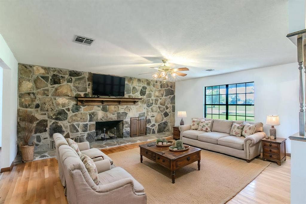 118 Spring Lake Drive, Lacy Lakeview, TX 76705 Stone-faced fireplace with a wood mantle, wood-finish flooring, and a ceiling fan