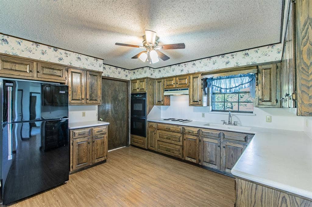 118 Spring Lake Drive, Lacy Lakeview, TX 76705 Kitchen featuring wood-finish cabinetry, white countertops, a built-in double oven, and a ceiling fan. Refrigerator does not convey with the property.