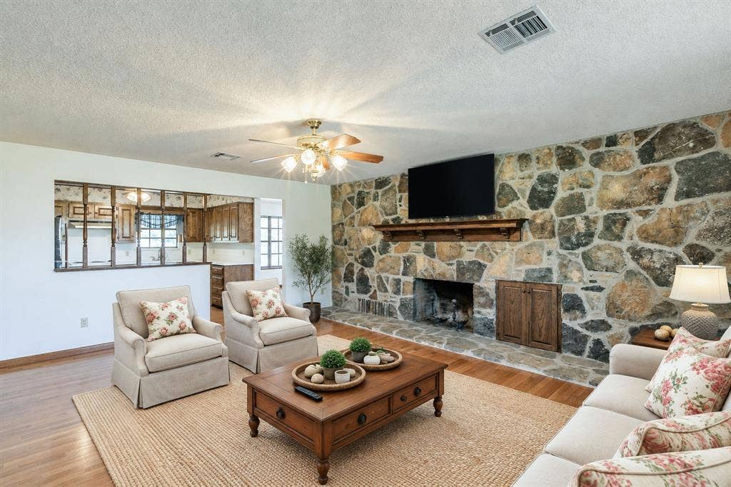 118 Spring Lake Drive, Lacy Lakeview, TX 76705 Stone-clad fireplace with wood mantle, warm wood-finish flooring, and a ceiling fan with integrated lighting