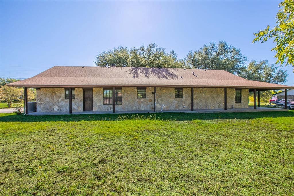 118 Spring Lake Drive, Lacy Lakeview, TX 76705 Stone-clad exterior, dark-framed windows, and an extensive covered porch which wraps around the home.