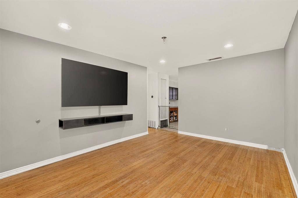 Recessed lighting, wood-finish flooring, built-in media console, and a wall-mounted television