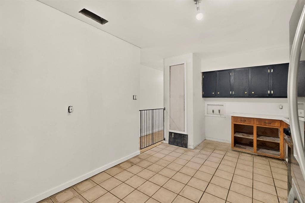 Tile flooring, black upper cabinetry, and partial wood-finish lower cabinetry