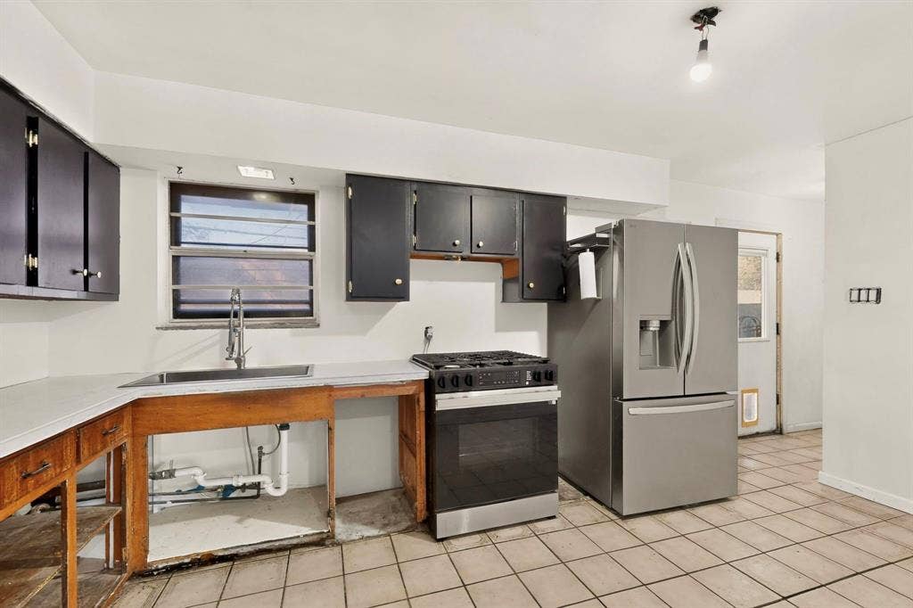 Kitchen featuring tile flooring, stainless steel range, stainless steel refrigerator, and dark wood-finish cabinetry